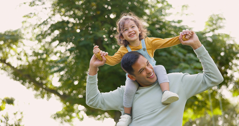 Dad carrying his daughter on his shoulders and smiling.